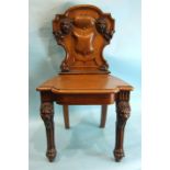 A Victorian walnut hall chair, the carved back with vacant central shield boss and carved lion's