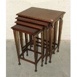 A 20th century mahogany nest of four rectangular-top tables, on turned tapered legs joined by