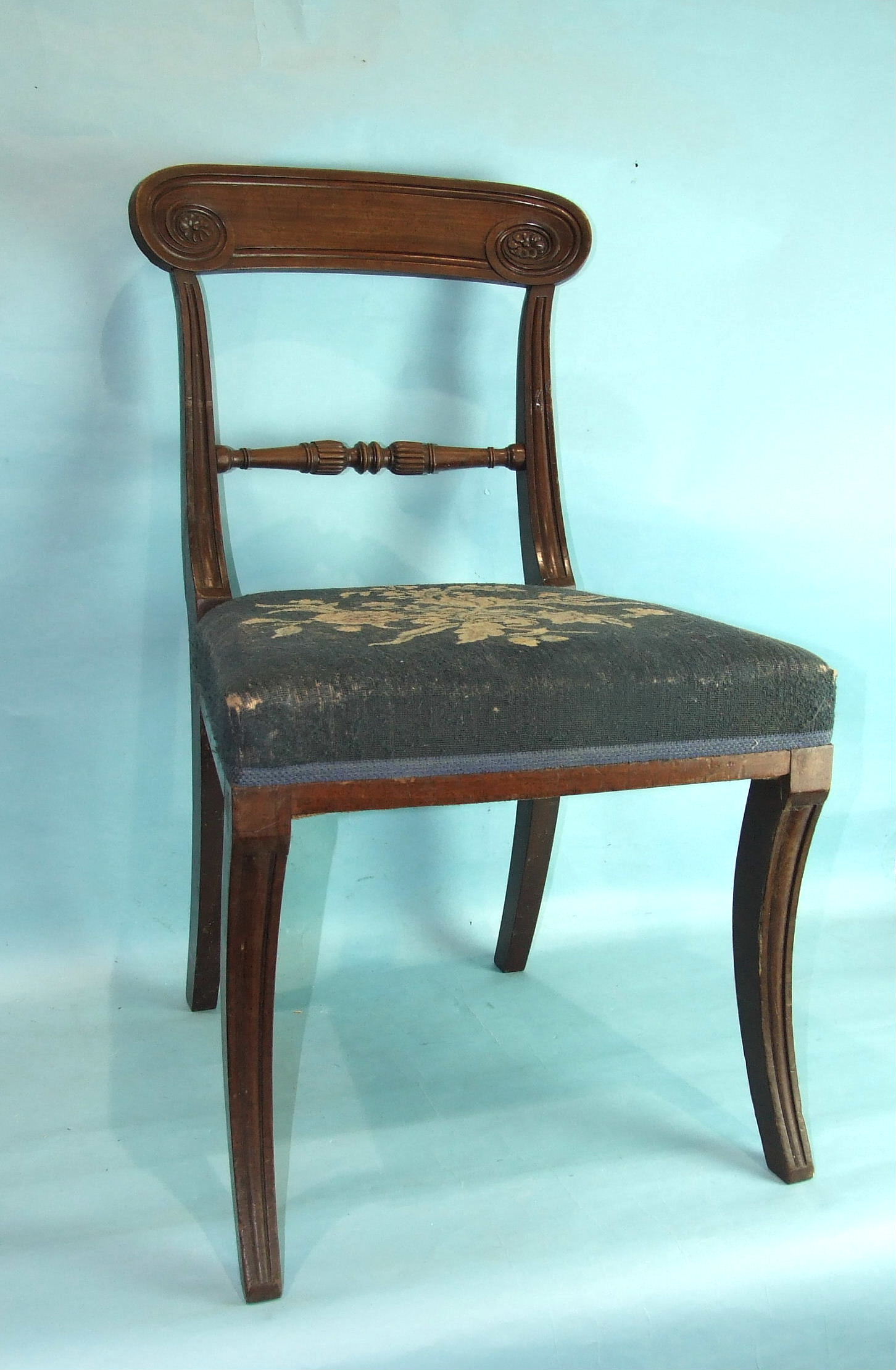 A set of six George IV mahogany sabre-legged dining chairs, each with carved top rail, centre bar