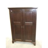 An antique oak enclosed narrow bookcase, having a pair of panelled doors, 90cm wide, 132cm high.