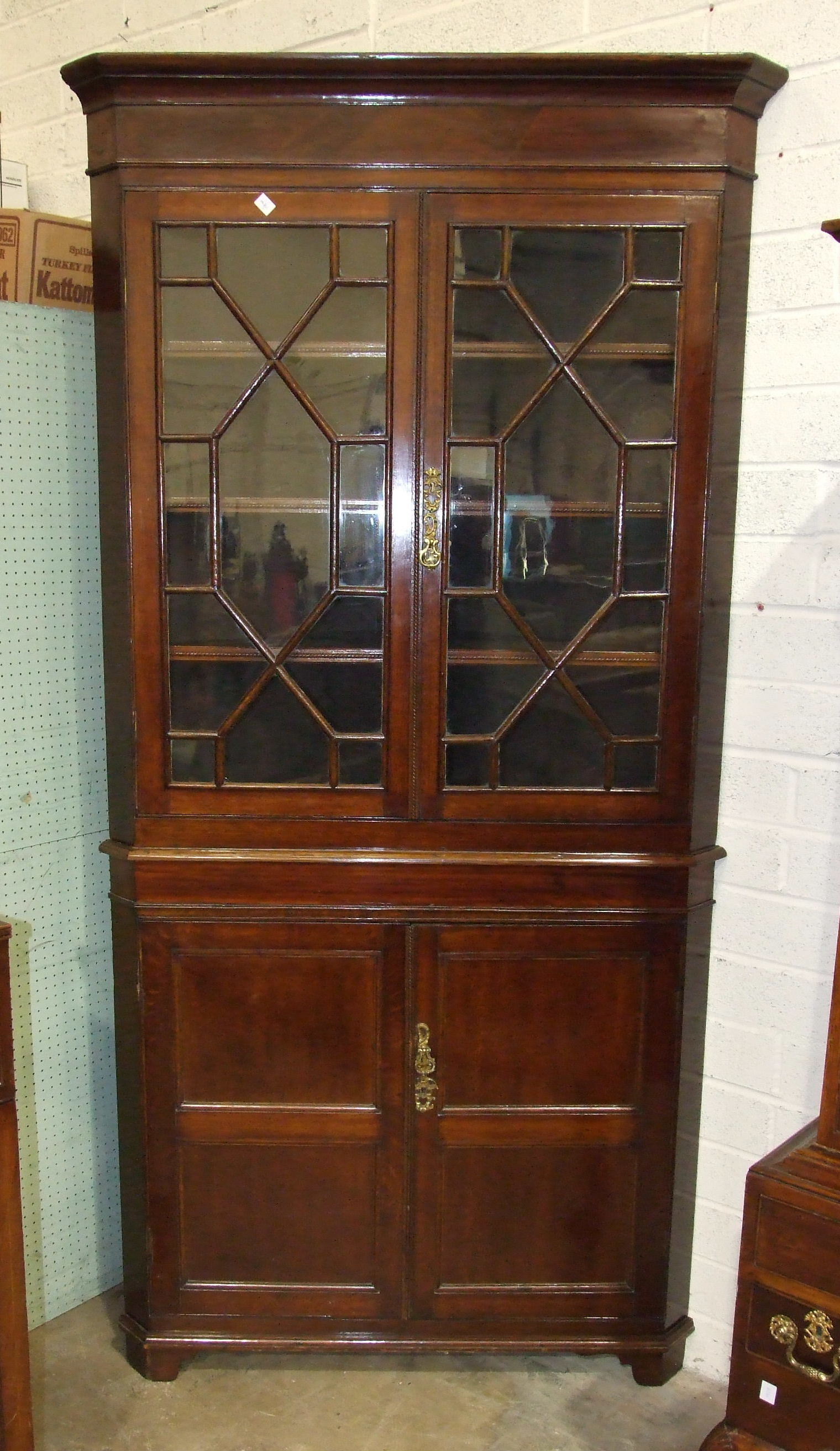 An antique oak and mahogany corner cupboard, having a pair of astragal-glazed doors, above a pair of