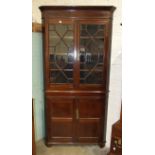 An antique oak and mahogany corner cupboard, having a pair of astragal-glazed doors, above a pair of