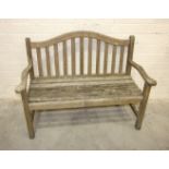 A teak garden bench with arched back and outswept arms, 130cm wide.