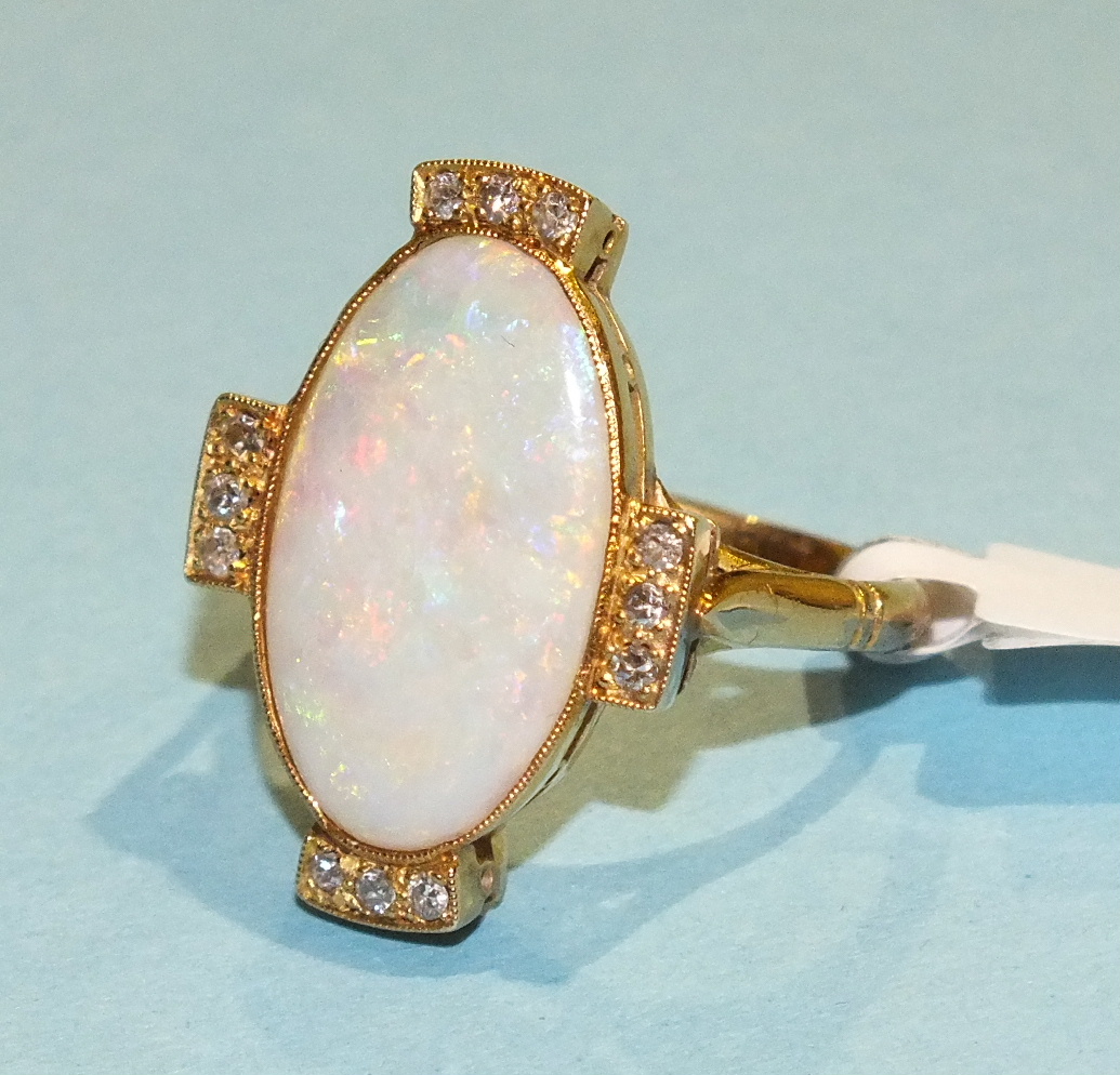 An opal and diamond cluster ring, the large oval opal (19 x 11.5mm), millegrain-set with trios of