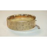 A 9ct gold hinged bangle with engraved geometric decoration, 27g.