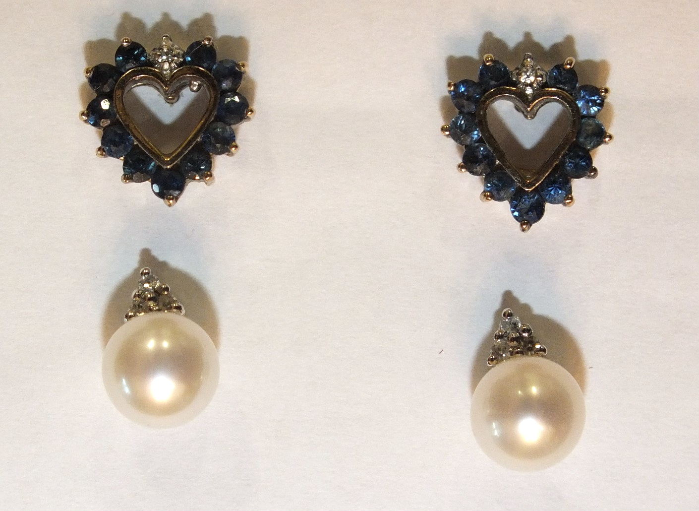 A pair of 9ct gold heart-shaped ear studs, each set eleven small round-cut sapphires and a diamond