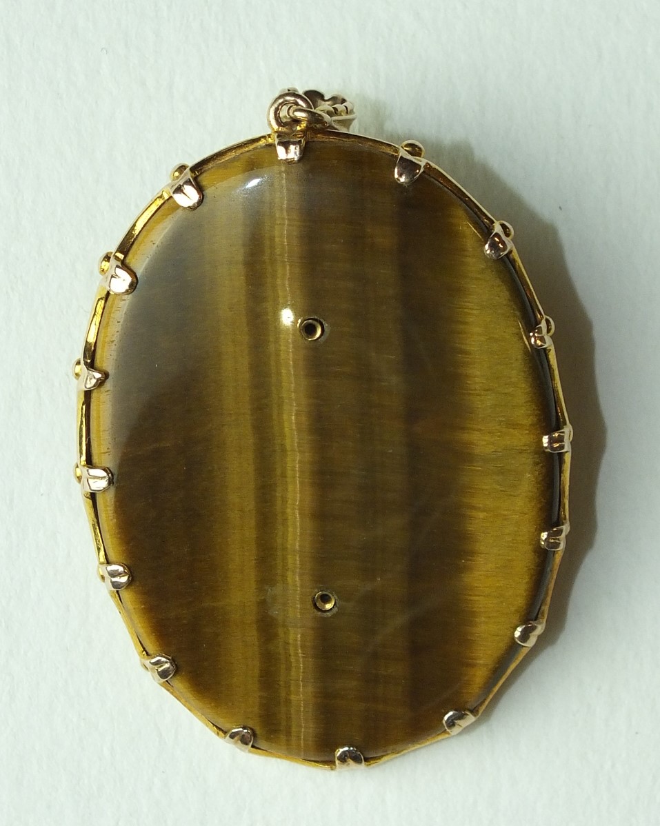 A large oval tiger's eye pendant overlaid with a gold profile in high relief of a young woman with - Image 2 of 2