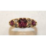 An 18ct yellow gold ring set three garnets, with pairs of rose-cut diamonds between, size K, 3.4g.