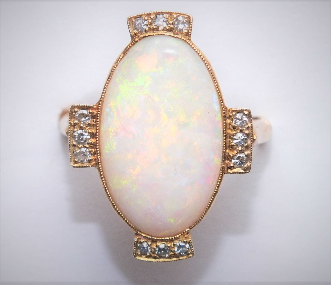 An opal and diamond cluster ring, the large oval opal (19 x 11.5mm), millegrain-set with trios of - Image 3 of 3