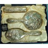 A reproduction silver dressing table set embossed with winged cherubs, in fitted case.