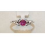 A ruby and diamond cluster ring claw-set a round-cut ruby between two triplets of brilliant-cut