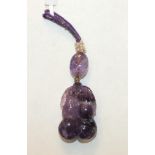 A Chinese carved amethyst pendant in the form of two gourds with leaf and tendrils, on an amethyst