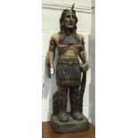 A carved wooden figure of a Red Indian holding a tomahawk and bow and carrying a quiver on his back,