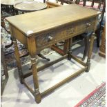 An oak finish rectangular-top hall table fitted with a single drawer, on turned legs.