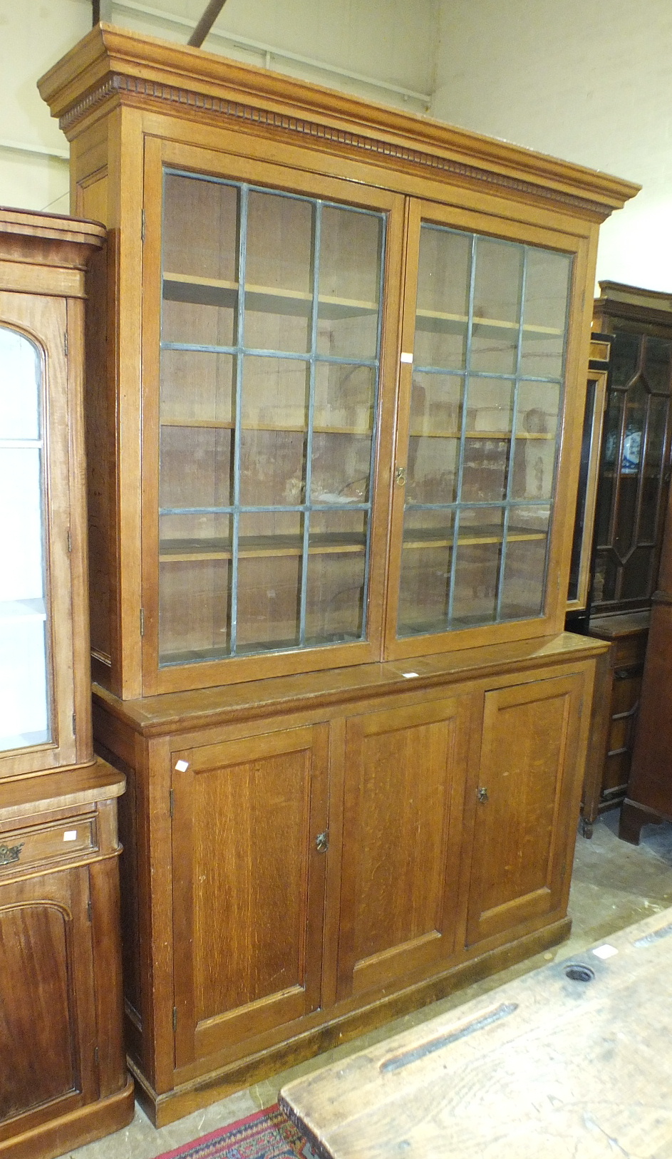 An early-20th century large oak bookcase, the dentil cornice above two leaded-light glazed doors and