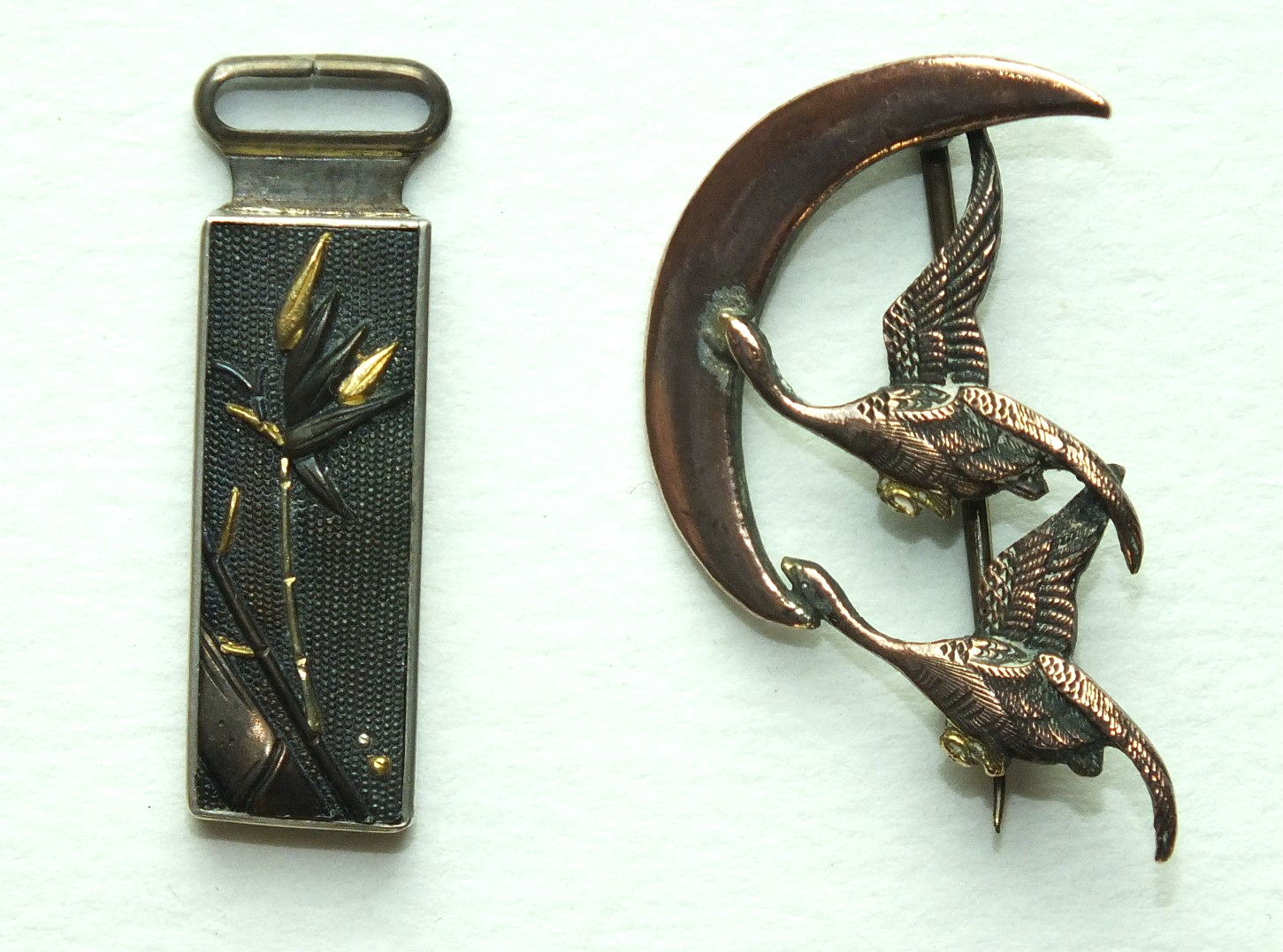 A small oblong Shakudo pendant with bamboo decoration, 32mm long, a brooch in the form of two