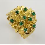 1970's emerald cluster ring, nine round cut emeralds, set on textured floral motif, mounted in