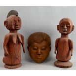 A West-African carved wooden mask, together with two carved red wood figures, the largest 40 cm