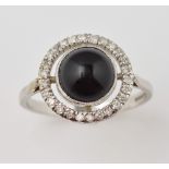 Onyx and diamond halo style ring, the central cabochon stone within a border of diamonds, set in