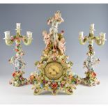 German porcelain clock garniture with figural and floral encrusted decoration, the candelabra with