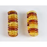 A pair of matching amber expanding bracelets, curved sections of heated amber in three colours,