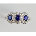 Sapphire and diamond three stone ring, set with oval sapphires of good colour within a border of