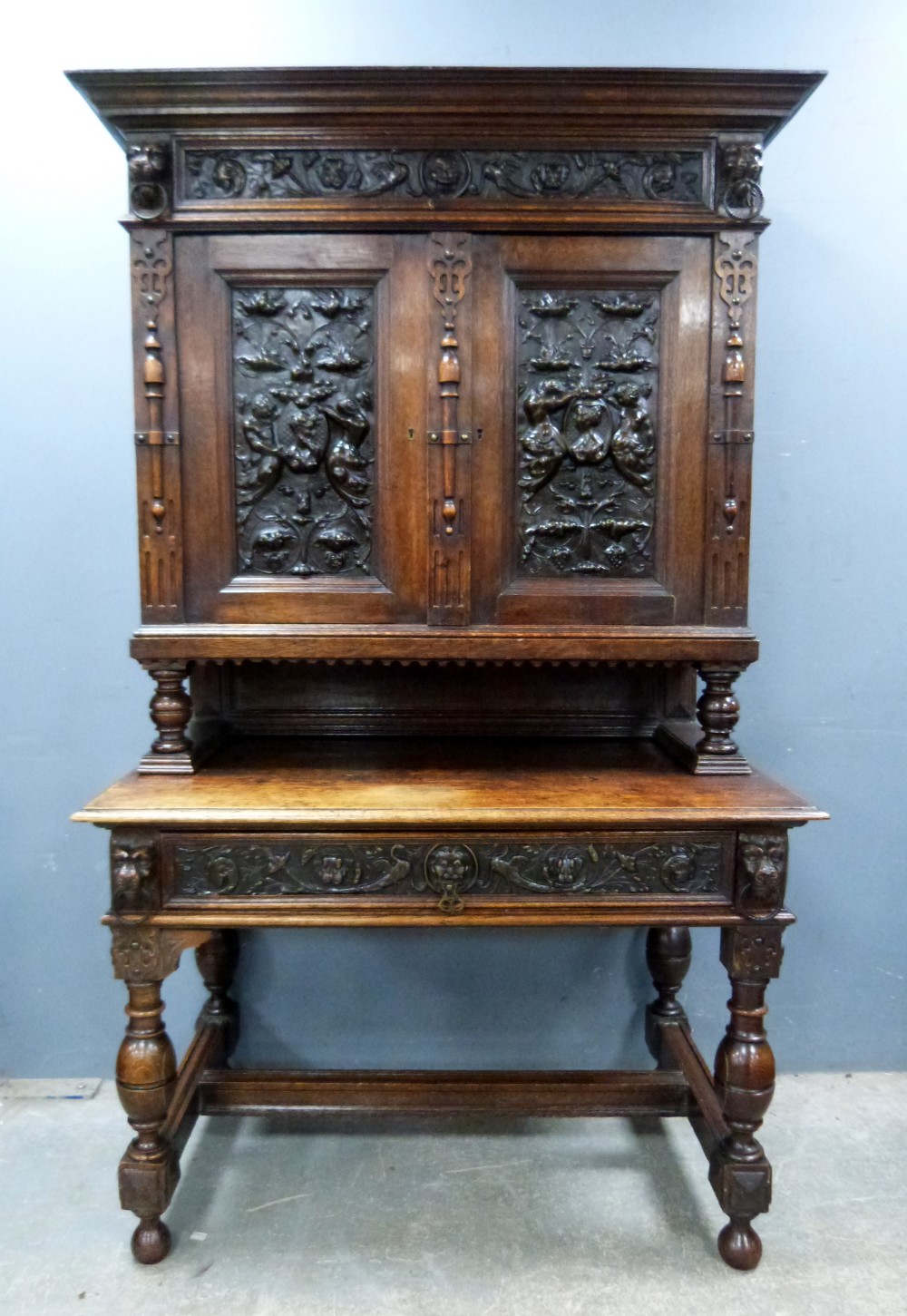 Late 19th century oak cabinet on stand with carved and embossed metal decoration of figures, the