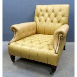 Leather button back armchair in pale mustard colour on turned legs with castors..