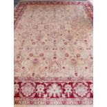 A cream ground Persian type carpet with main red border, centre with repeating foliate forms, 450