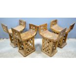 Four African wooden stools, possibly Fon, with curved seats and chequer-board bases, 60 cm high,