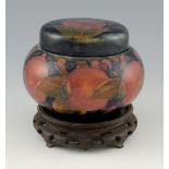 Moorcroft tobacco jar, pomegranate design together and associated wooden base, 13 cm high . small