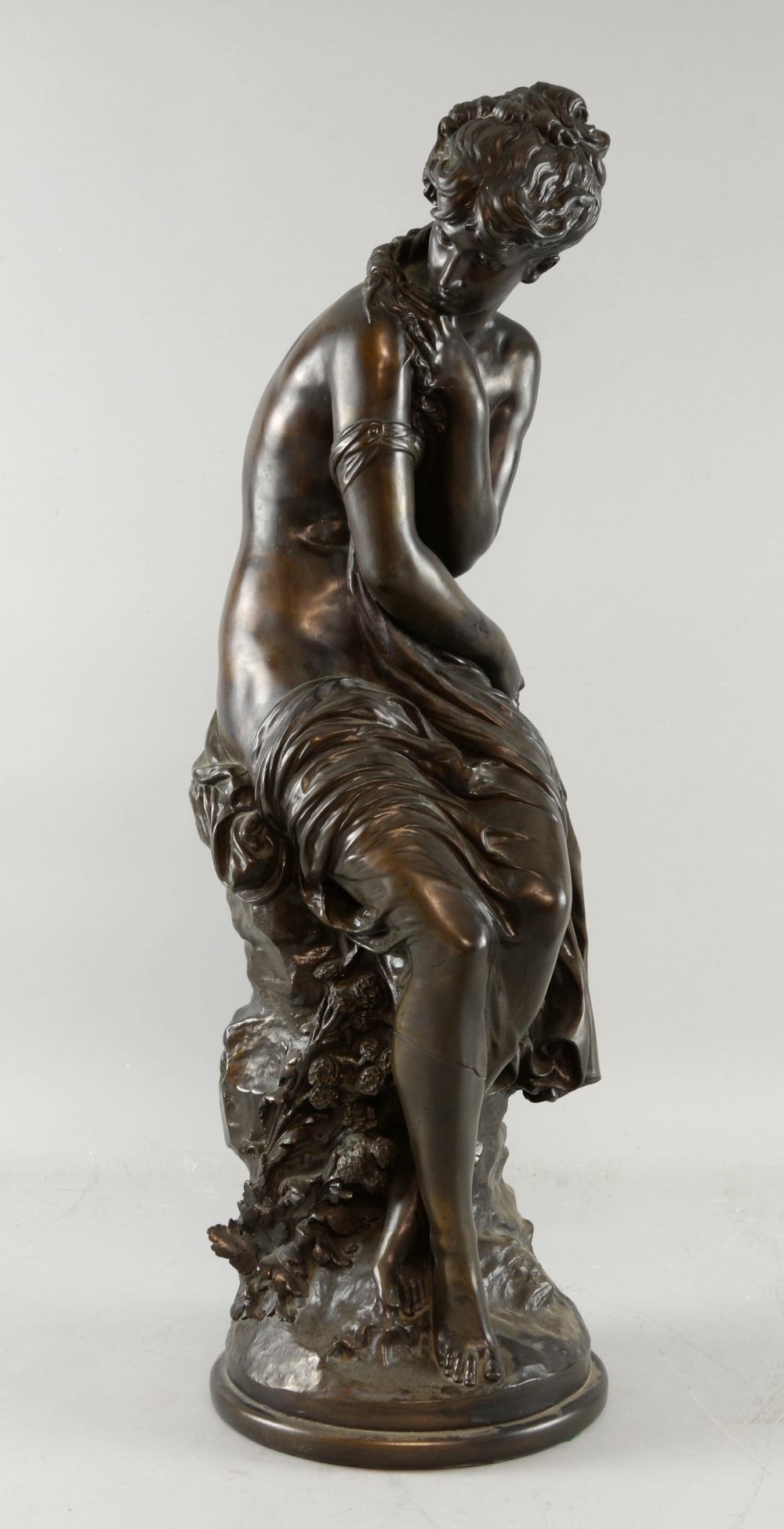 After Auguste Moreau, bronze figure of a semi clad maiden seated and holding flowers, signed in the