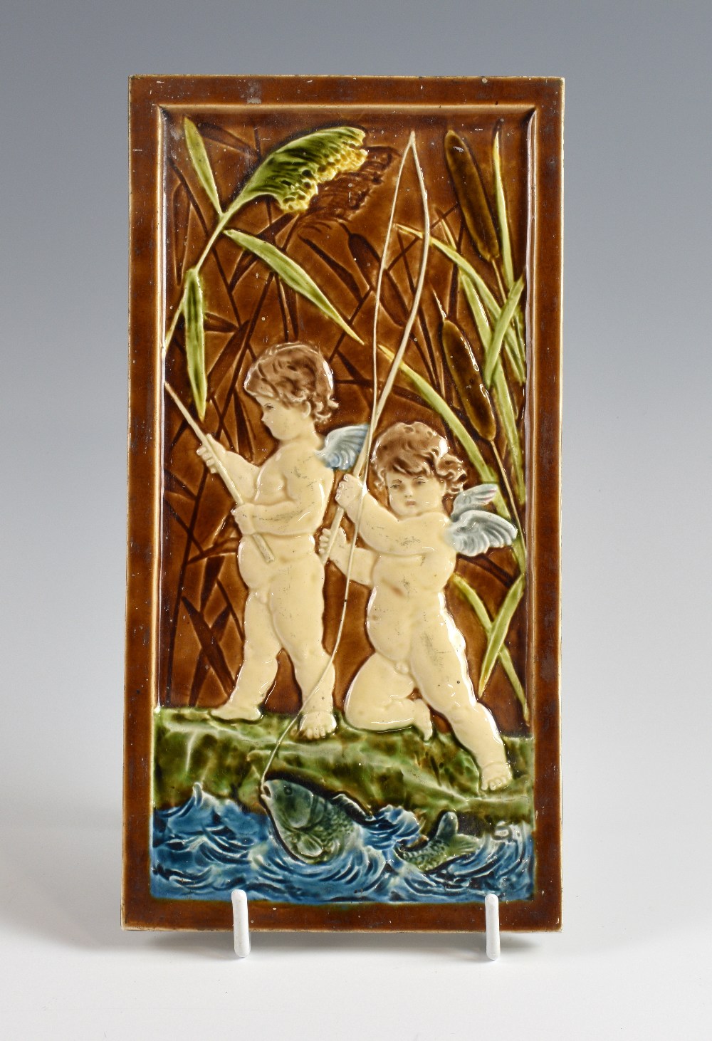Villeroy & Boch, a tile depicting cherubs and a fish stamped VB to reverse, 18 x 31 cm. Glazed area