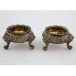 Pair of Victorian silver salts with embossed decoration, each on three lion mask and paw feet, by