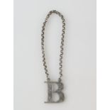Victoria silver decanter label, in the form of an openwork letter B with bright-cut engraving, by