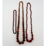Red Bakelite necklace of graduating oval beads an imitation amber necklace and another with