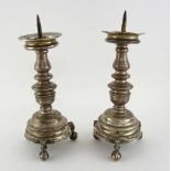 Pair of silver pricket candlesticks on round bases and three feet with male masks and ball and