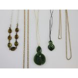 Two carved nephrite jade pendants, largest 6.7 cm, a bracelet of treated amber, gold plated chains