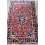 Persian type red ground rug with a central floral medallions and a main blue ground border and