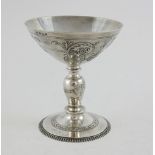 Silver Tassie cup the bowl applied with flower heads and scroll work, on a pedestal foot