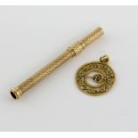 Gold tooth pick in engine turned case, unmarked, and pendant depicting a cannon within ivy leaf