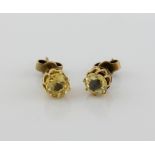 Two yellow sapphires set in earrings, one oval estimated at 1.09 carats and a round stone of 0.98