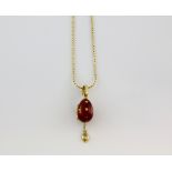 Faberge a contemporary gold and enamel egg pendant, the red enamel inlaid with gold stars and