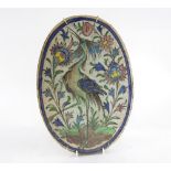 Oval Persian tile painted with polychrome painting of a bird among flowers, 38 x 26.5 cm .