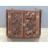 Black Forest style carved oak wall hanging corner cupboard with flowers and vines, 38cm x 50cm.
