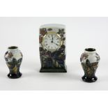 Moorcroft clock in blackberry and bramble pattern 15 cm, and a matching pair of vases, 9.5 cm,