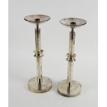 Pair of silver candlesticks, each with hammered finish, with wasted columns semi-circular nozzles