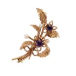 A 9ct gold cultured pearl and amethyst floral brooch. Designed as a textured foliate spray, with