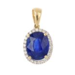 A glass-filled sapphire and diamond cluster pendant. The oval-shape glass-filled sapphire, with a