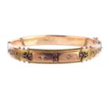 An Edwardian 9ct gold gem-set hinged bangle. Designed as two star-set old-cut diamond panels, with